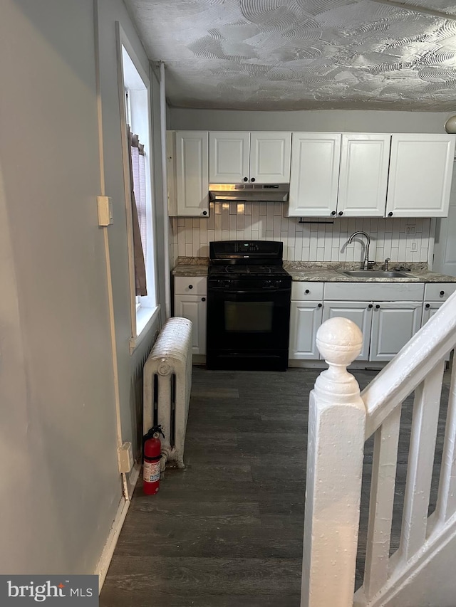 kitchen featuring black gas range, dark wood-type flooring, a sink, white cabinets, and radiator