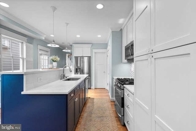 kitchen with a sink, white cabinets, light countertops, appliances with stainless steel finishes, and crown molding