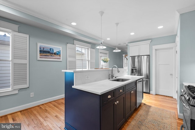 kitchen featuring light wood finished floors, a center island with sink, appliances with stainless steel finishes, light countertops, and a sink