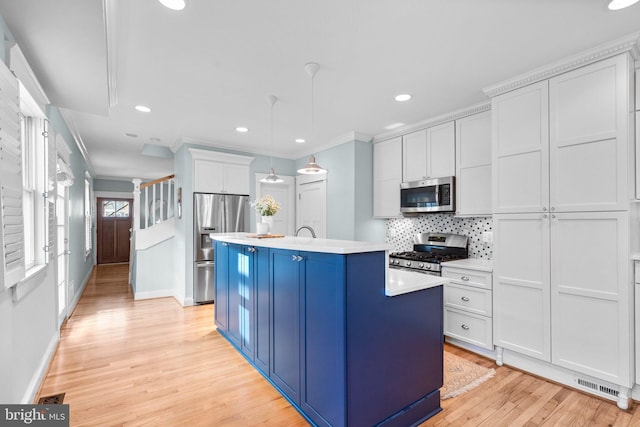 kitchen featuring blue cabinets, crown molding, stainless steel appliances, and light countertops