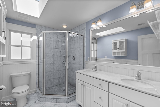 bathroom with a skylight, a wainscoted wall, and a sink