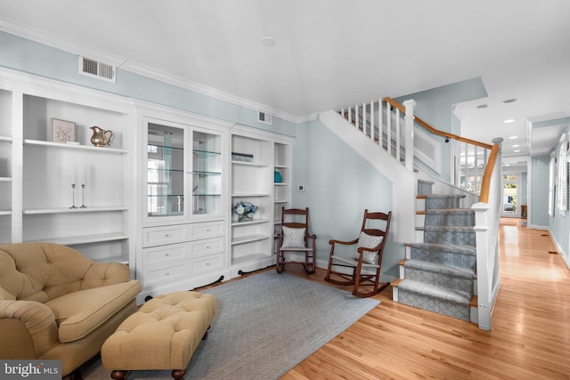 living area with baseboards, stairs, visible vents, and wood finished floors