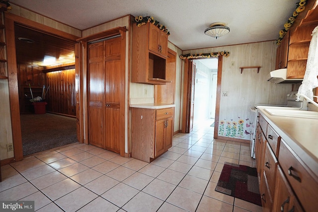 kitchen with light tile patterned floors, wooden walls, light countertops, range, and open shelves