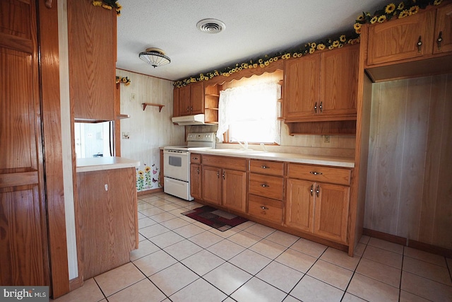 kitchen with brown cabinets, electric range, visible vents, and light countertops