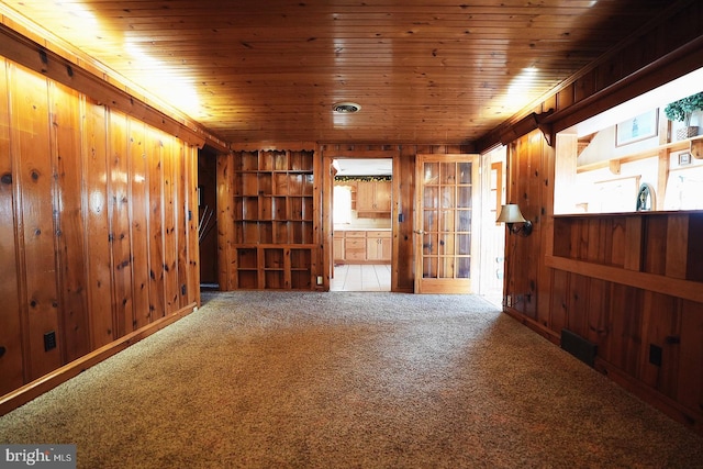 carpeted spare room with wood walls and wooden ceiling