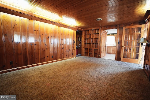 empty room featuring wooden ceiling, wood walls, and carpet