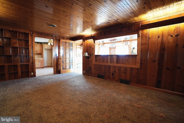 unfurnished room with wooden ceiling, carpet flooring, and wood walls