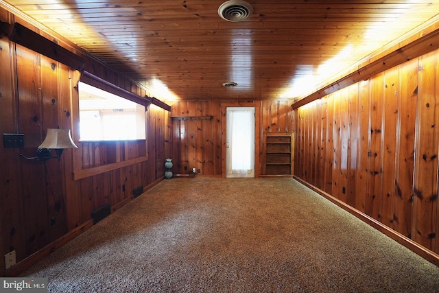 interior space with visible vents, carpet flooring, wood walls, wooden ceiling, and baseboards