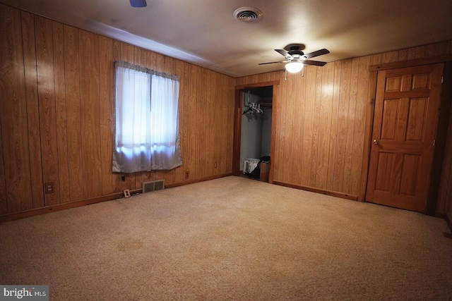 unfurnished bedroom with wood walls, carpet flooring, visible vents, and baseboards