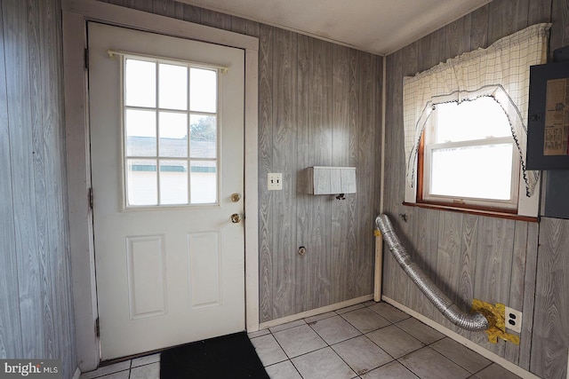 doorway to outside with plenty of natural light, wood walls, and light tile patterned floors