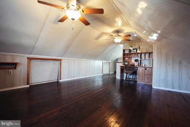 additional living space with lofted ceiling, dark wood-type flooring, baseboards, and wooden walls