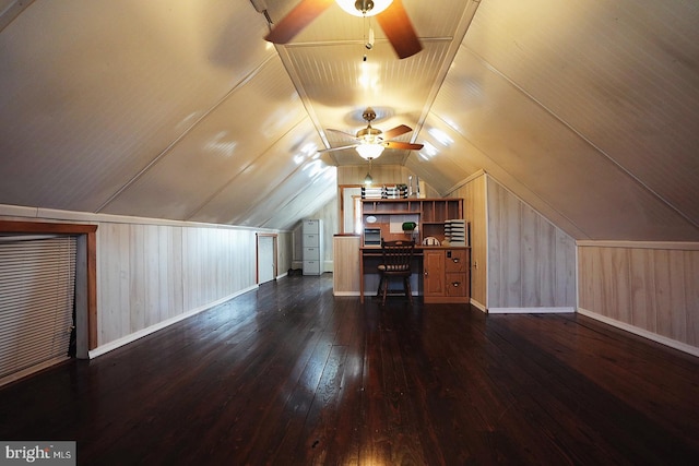 unfurnished office with lofted ceiling, ceiling fan, wooden walls, baseboards, and dark wood finished floors