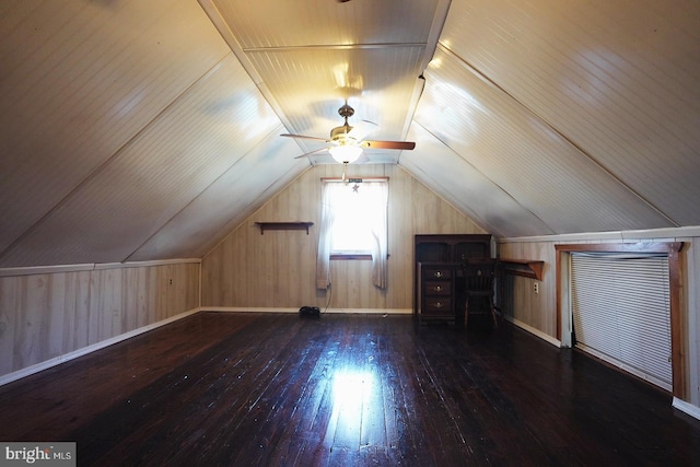 additional living space featuring lofted ceiling, a ceiling fan, wooden walls, baseboards, and hardwood / wood-style flooring