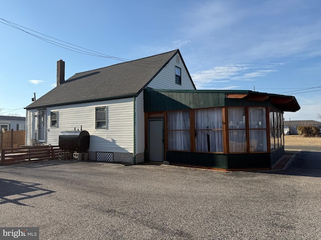 view of home's exterior with crawl space, roof with shingles, a chimney, and heating fuel