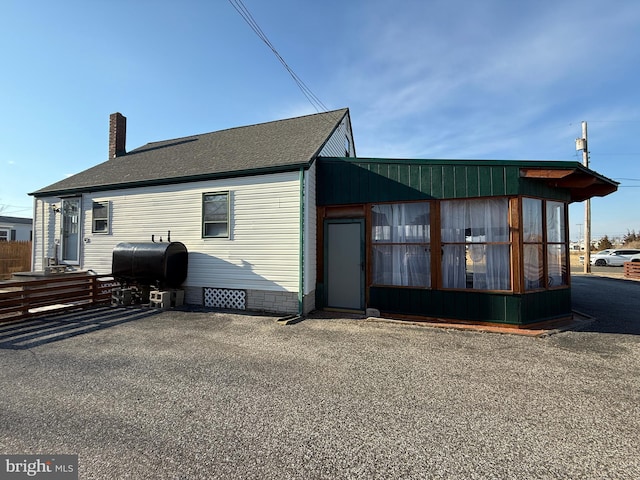 exterior space featuring a shingled roof, crawl space, a chimney, and heating fuel