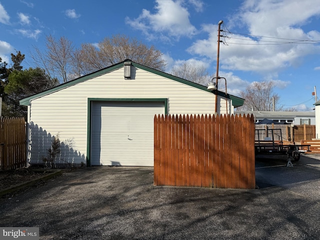 detached garage featuring fence and aphalt driveway