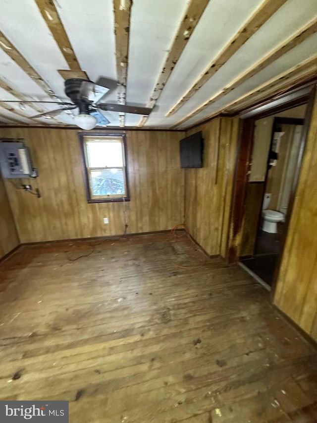 below grade area with hardwood / wood-style floors, wood walls, and electric panel