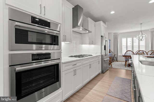 kitchen with backsplash, stainless steel appliances, wall chimney exhaust hood, and light countertops