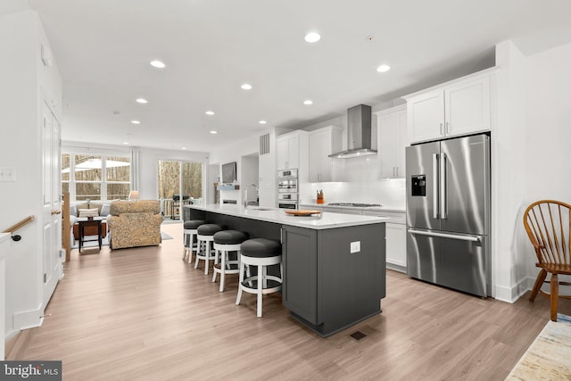 kitchen featuring white cabinets, appliances with stainless steel finishes, and wall chimney range hood