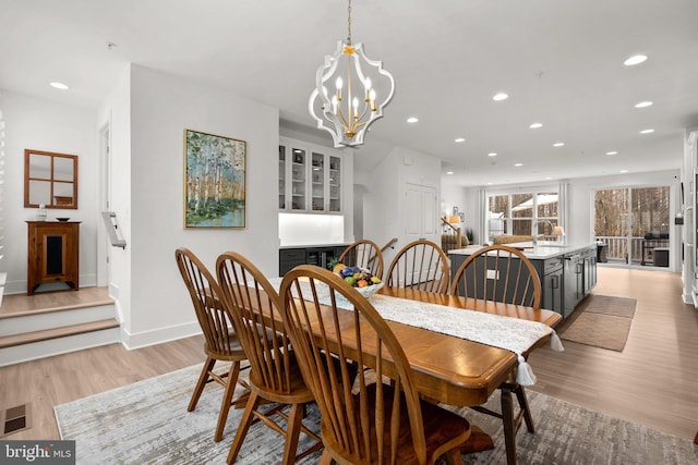 dining room with baseboards, light wood finished floors, recessed lighting, a dry bar, and a chandelier