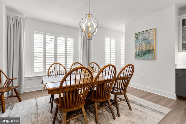 dining room with baseboards, an inviting chandelier, and light wood finished floors