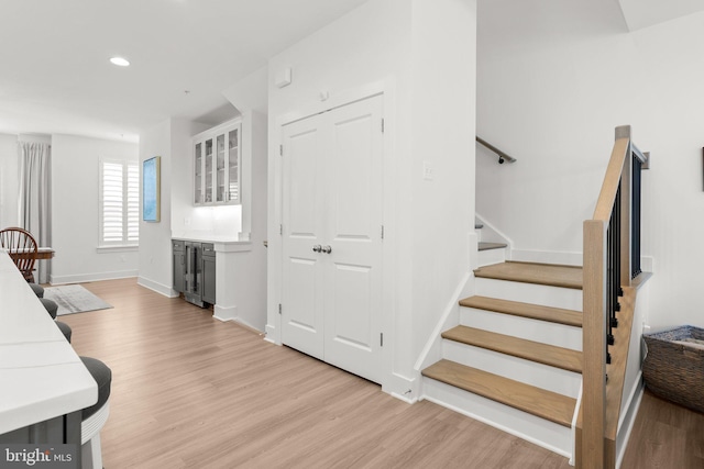 staircase with recessed lighting, baseboards, wine cooler, and wood finished floors