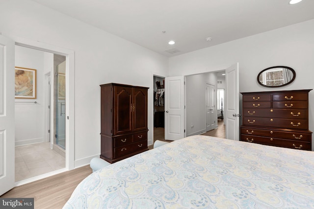 bedroom featuring baseboards, ensuite bath, recessed lighting, a spacious closet, and light wood-type flooring