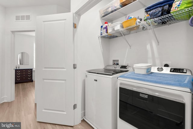 clothes washing area with independent washer and dryer, laundry area, light wood-style flooring, and visible vents