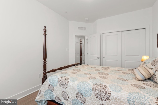 bedroom with visible vents, baseboards, a closet, and wood finished floors