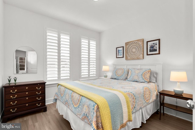 bedroom featuring multiple windows, wood finished floors, and baseboards