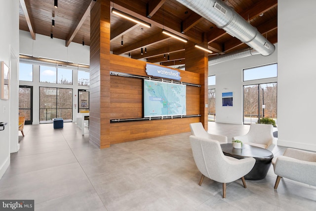 interior space with beamed ceiling, visible vents, a high ceiling, wood walls, and wood ceiling