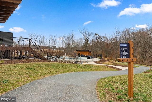 view of home's community featuring stairway, a yard, and a swimming pool