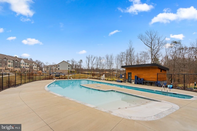 community pool featuring a patio area, fence, and a residential view