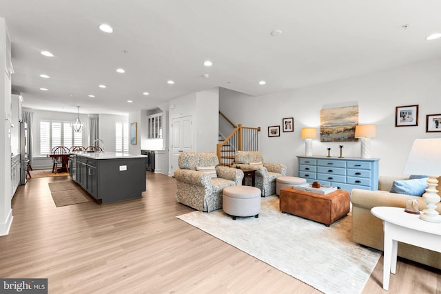 living area with a notable chandelier, recessed lighting, stairs, and light wood-style floors