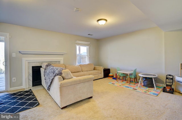 living room with baseboards, carpet flooring, and a tiled fireplace