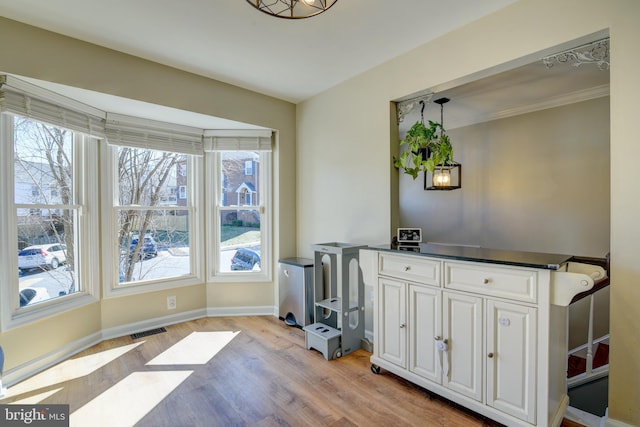 office with ornamental molding, baseboards, visible vents, and light wood finished floors