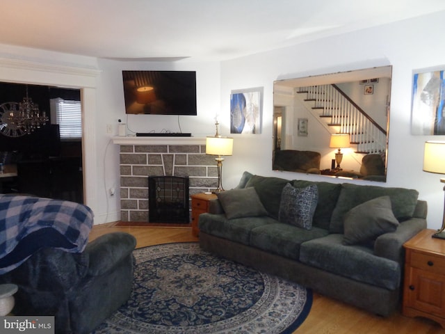 living area featuring stairs, a fireplace, wood finished floors, and a notable chandelier