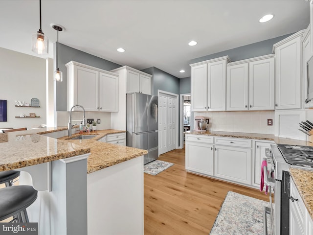 kitchen featuring appliances with stainless steel finishes, white cabinetry, decorative light fixtures, and a kitchen breakfast bar