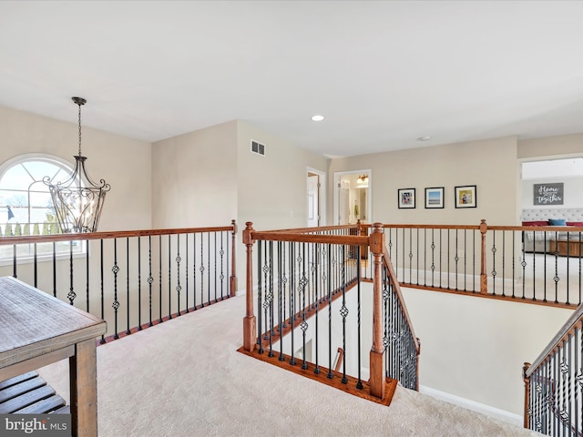 hallway with carpet floors, recessed lighting, visible vents, an upstairs landing, and a chandelier