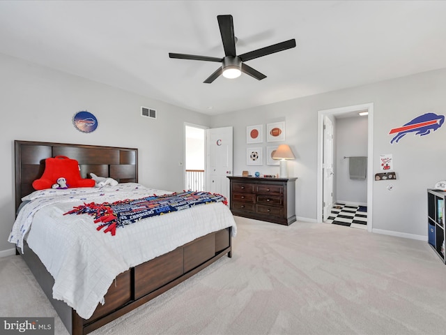 bedroom with light carpet, baseboards, visible vents, ensuite bath, and ceiling fan