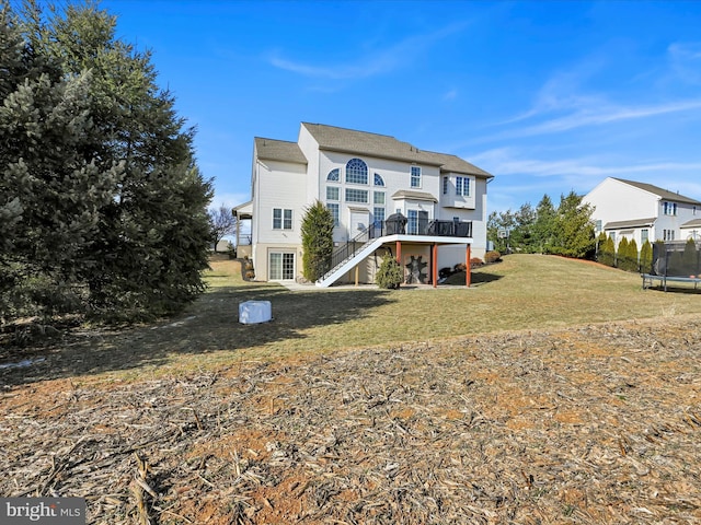 back of property with a yard, a trampoline, stairway, and a wooden deck