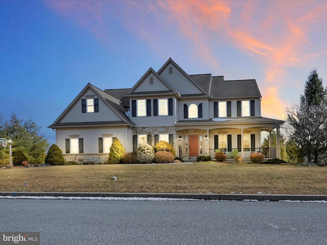 view of front of house with stone siding, a porch, and a front lawn