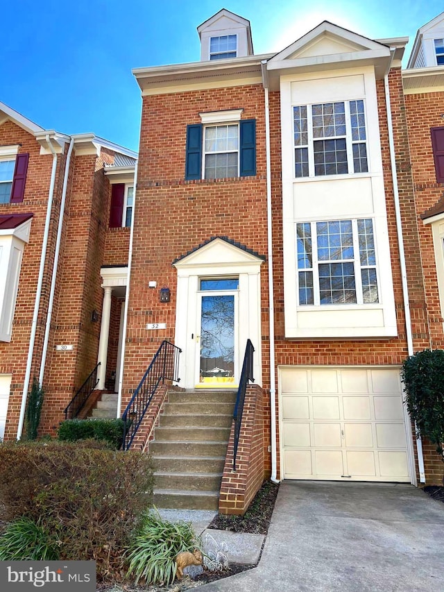 multi unit property featuring a garage, concrete driveway, and brick siding