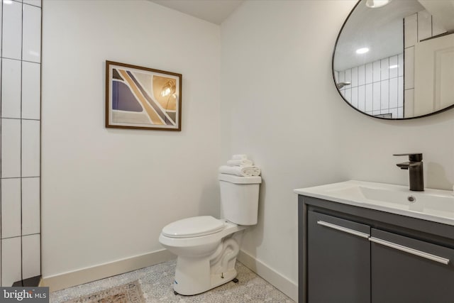 bathroom with vanity, toilet, baseboards, and speckled floor