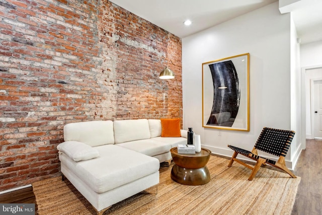 living area featuring recessed lighting, baseboards, wood finished floors, and brick wall