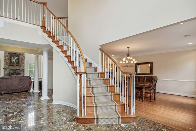 stairs with baseboards, a towering ceiling, marble finish floor, crown molding, and a fireplace