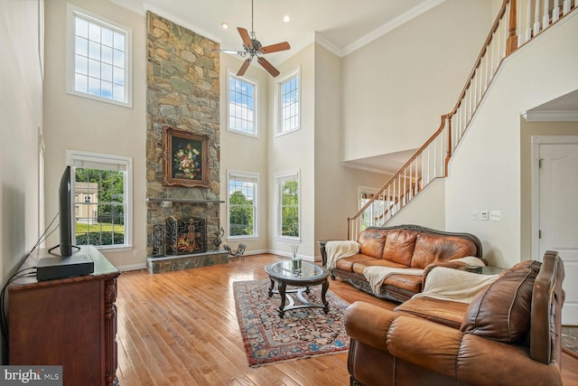 living room featuring baseboards, a fireplace, light wood-style flooring, and crown molding