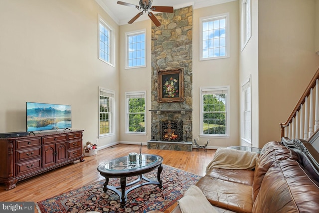 living area featuring a healthy amount of sunlight, light wood-style flooring, baseboards, and a stone fireplace