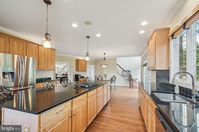 kitchen with stainless steel appliances, a kitchen island, a sink, ornamental molding, and pendant lighting