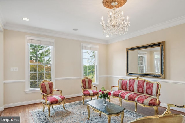 sitting room featuring an inviting chandelier, crown molding, baseboards, and wood finished floors